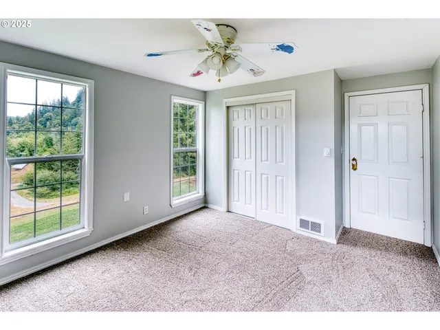 a view of a livingroom with a chandelier fan and windows