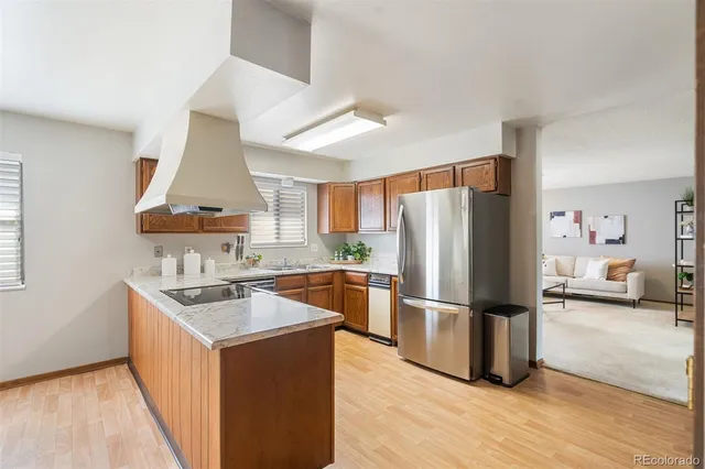 a kitchen with stainless steel appliances granite countertop a refrigerator a sink dishwasher a stove and white countertops with wooden floor