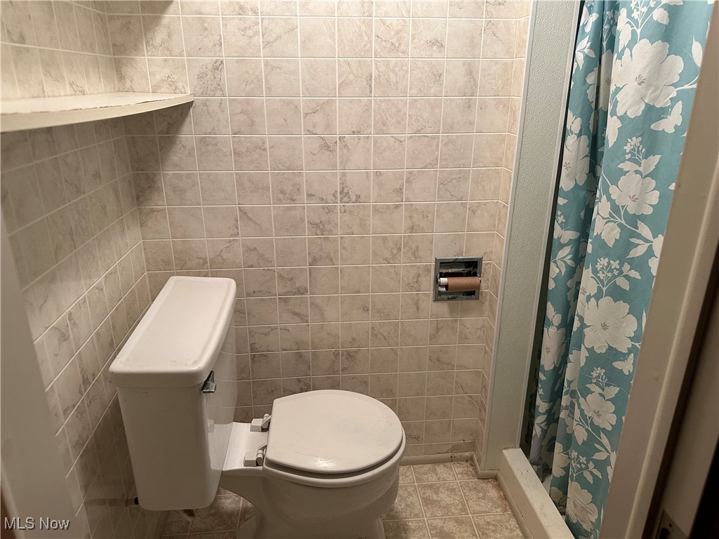 12303 Orme Road Garfield Heights, OH 44125 - Photo 22 of 22 Bathroom featuring tile patterned floors, toilet, a stall shower, and tile walls