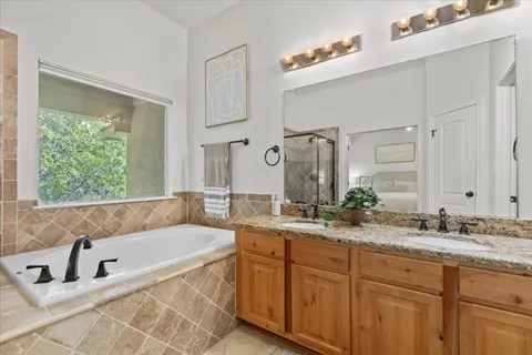 a bathroom with a granite countertop tub sink and mirror