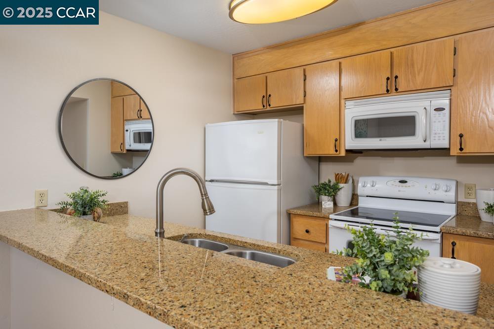 1455 Latour Lane, Unit 43 Concord, CA 94521 - Photo 6 of 17 a kitchen with stainless steel appliances granite countertop a stove a sink and a microwave