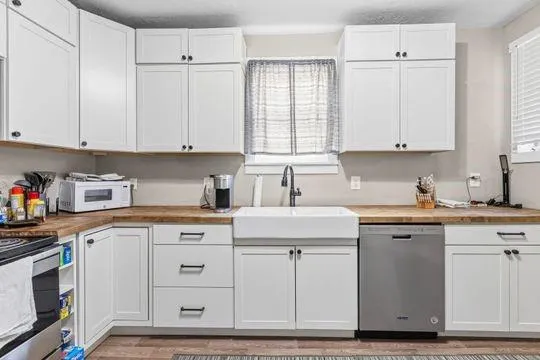 a kitchen with cabinets appliances a sink and a window
