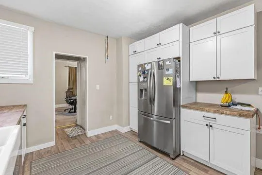 a kitchen with granite countertop a refrigerator and a wooden floor