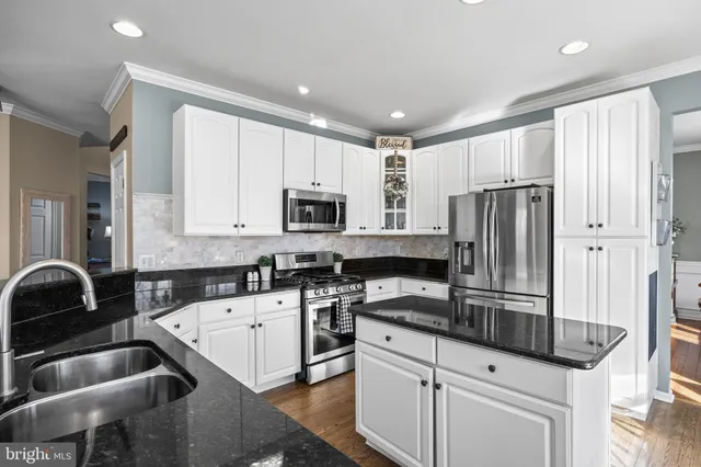 a kitchen with granite countertop a sink stainless steel appliances and white cabinets