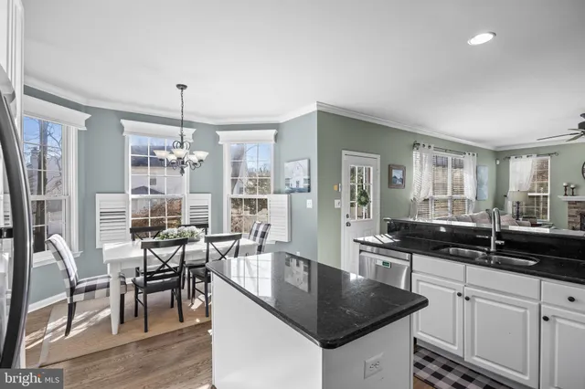 a kitchen with granite countertop a sink a counter space dining table and chairs