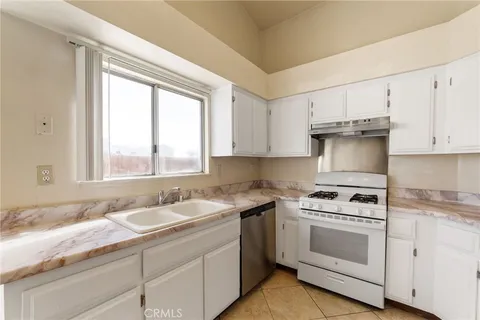 a kitchen with granite countertop white cabinets white appliances and a window
