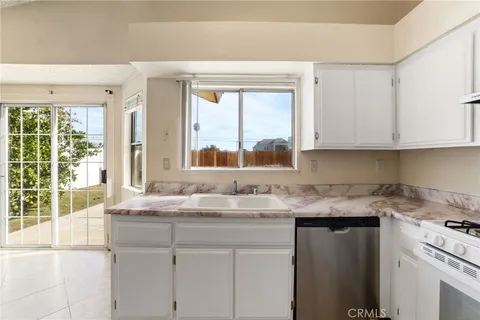 a kitchen with granite countertop white cabinets and a window