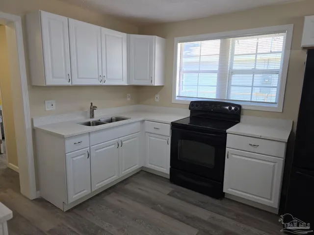 a kitchen with white cabinets appliances a sink and a window