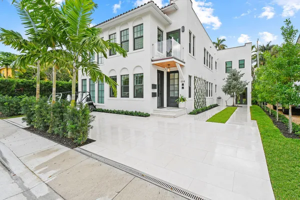a view of a white house with a swimming pool and lawn chairs next to a yard