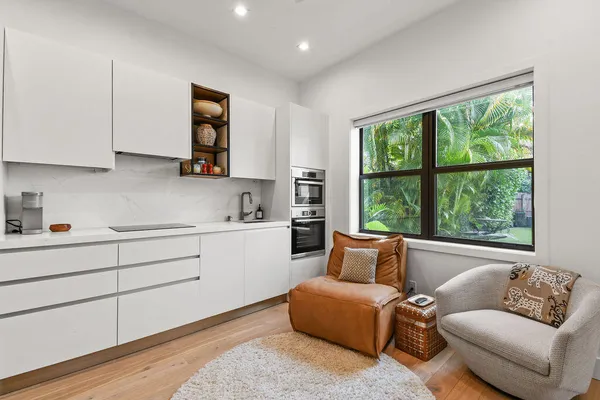 a kitchen with a white furniture a large window and a sink