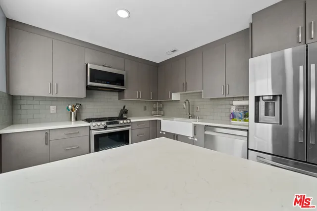 a kitchen with stainless steel appliances granite countertop a refrigerator sink stove and oven