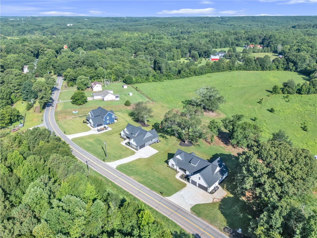1727 Harris Bridge Road Anderson, SC 29621 - Photo 33 of 35 An aerial perspective reveals newly built homes nestled in a verdant landscape, bordering a paved road and open fields.
