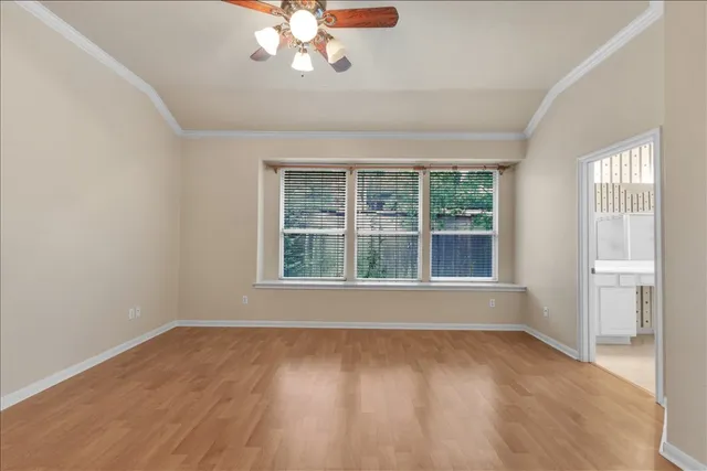 a view of an empty room with a window and wooden floor