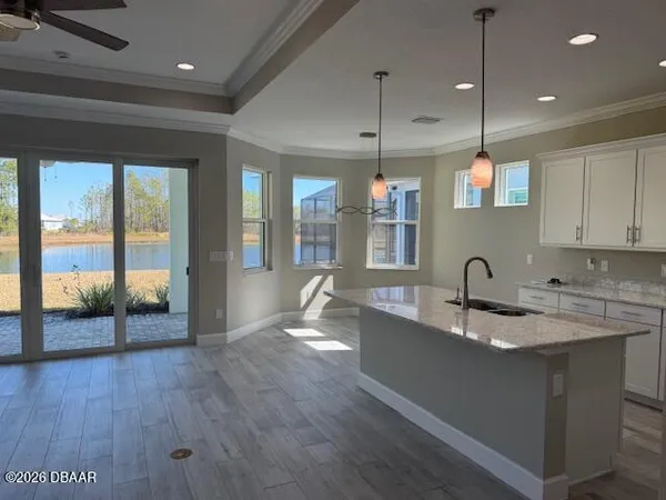 a large kitchen with stainless steel appliances granite countertop a sink a oven and a large window with wooden floors
