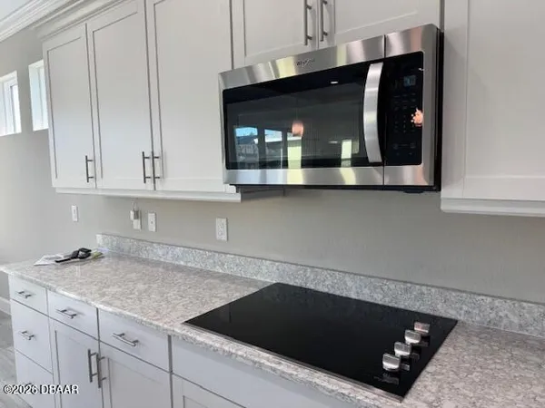a kitchen with granite countertop white cabinets and black appliances