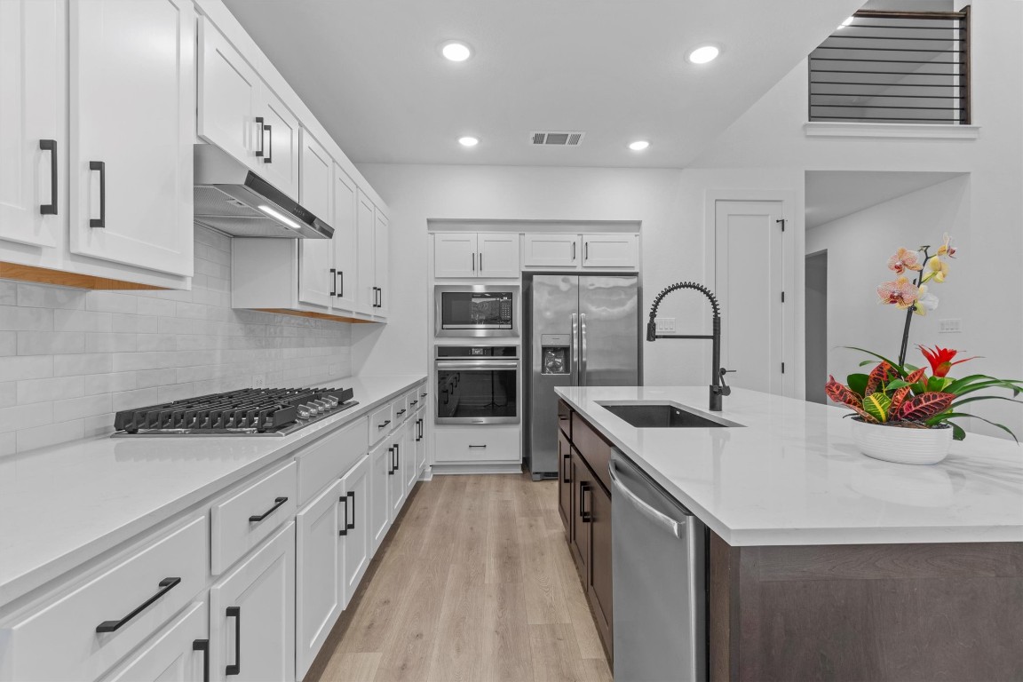 a kitchen with stainless steel appliances a sink stove and cabinets