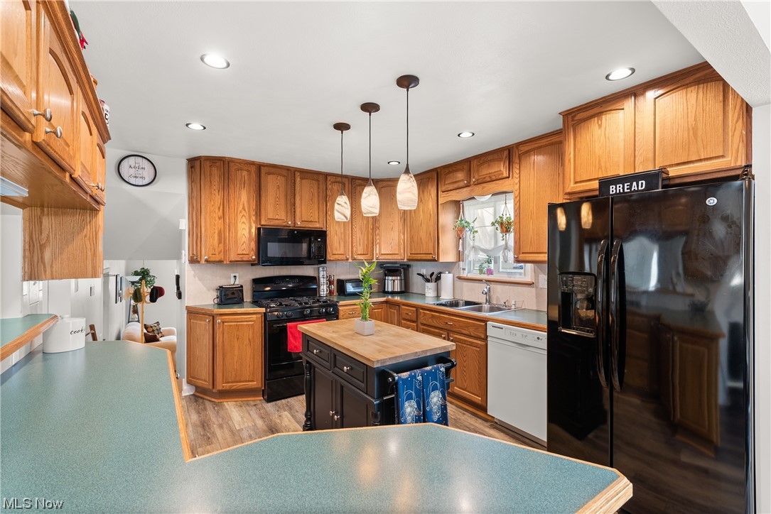 7094 Brandywine Road Parma Heights, OH 44130 - Photo 27 of 49 Kitchen featuring light hardwood / wood-style flooring, hanging light fixtures, sink, black appliances, and a kitchen island