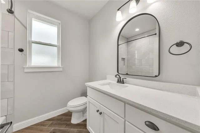 a bathroom with a toilet sink vanity and mirror