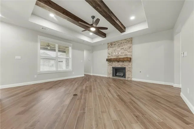 a view of an empty room with wooden floor fireplace and a window