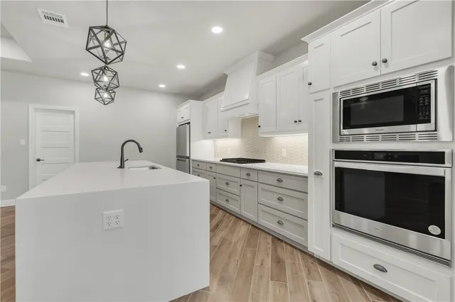 a kitchen with stainless steel appliances granite countertop a sink a stove a microwave and cabinets