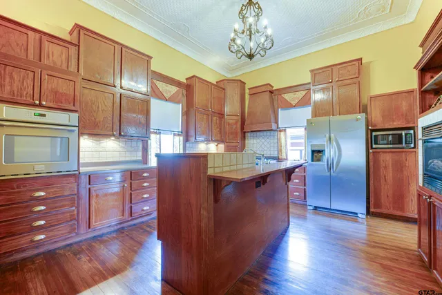 a kitchen with stainless steel appliances granite countertop a refrigerator a stove and a wooden floors