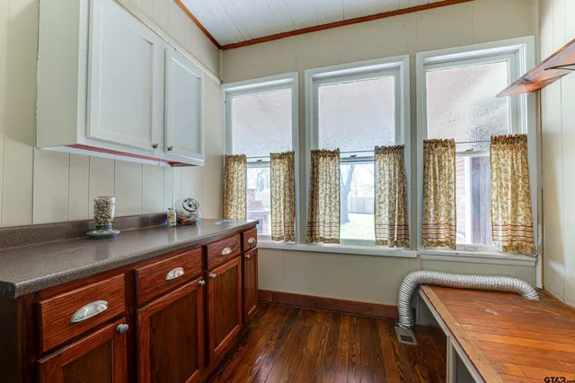 a kitchen with stainless steel appliances granite countertop a sink dishwasher a refrigerator and white cabinets with wooden floor