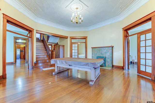 a dining room with wooden floor a chandelier a glass table and chairs