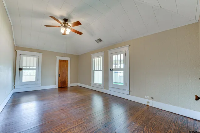 a view of an empty room with a window and wooden floor