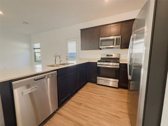 a kitchen with a refrigerator a microwave a sink and cabinets