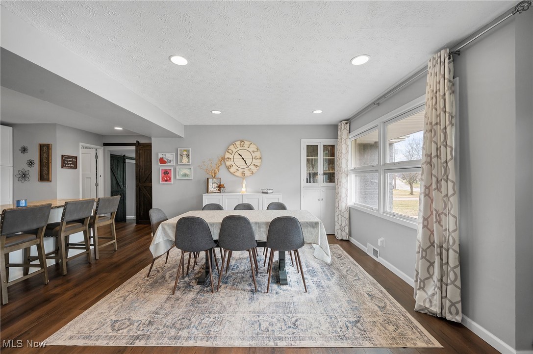 87 Kenridge Road Akron, OH 44333 - Photo 9 of 48 Dining area with dark wood-style floors, a textured ceiling, baseboards, and a barn door