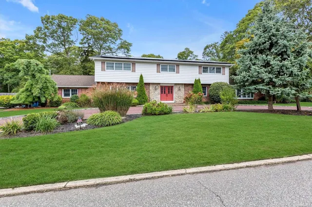 a view of a house next to a big yard and large trees