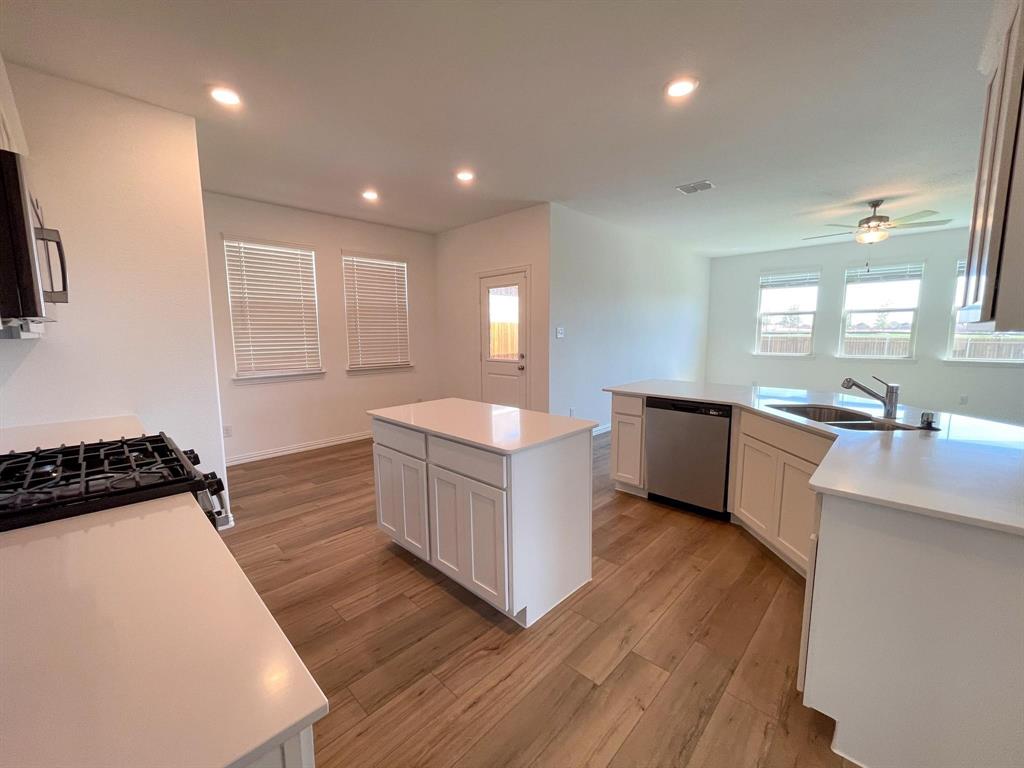 3305 Tulip Poplar Trail McKinney, TX 75071 - Photo 14 of 29 a large white kitchen with wooden floors and white stainless steel appliances