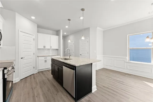 a kitchen with stainless steel appliances granite countertop a white cabinets and wooden floor