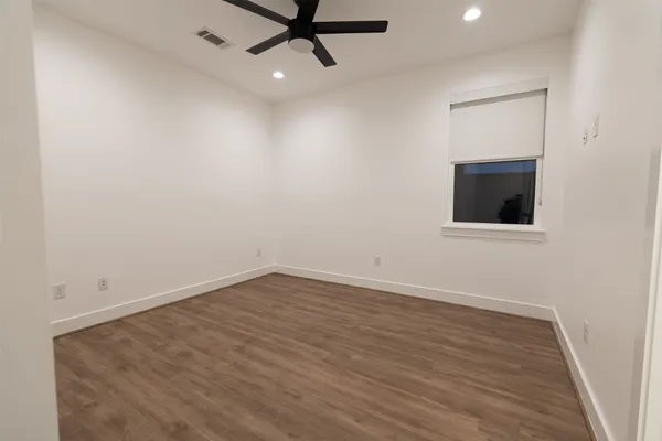 an empty room with wooden floor and windows