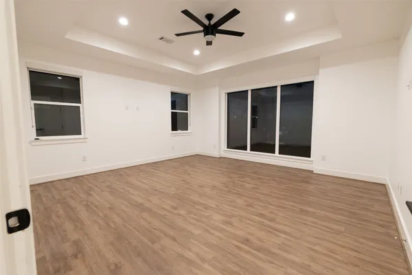 an empty room with wooden floor and windows