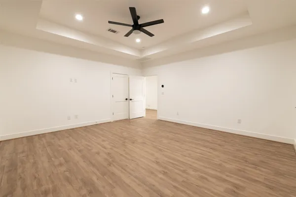 an empty room with wooden floor and ceiling fan