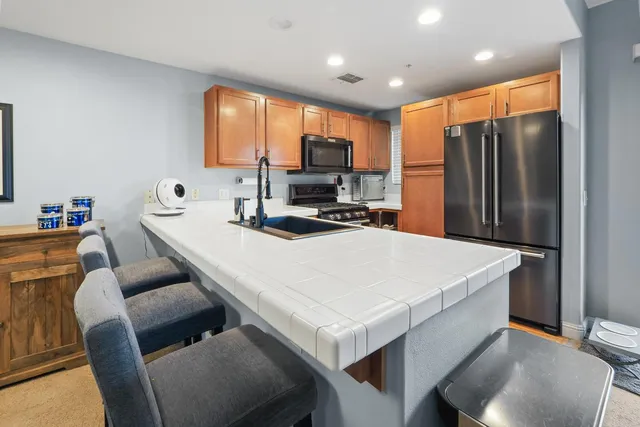 a kitchen with stainless steel appliances a table chairs and a refrigerator