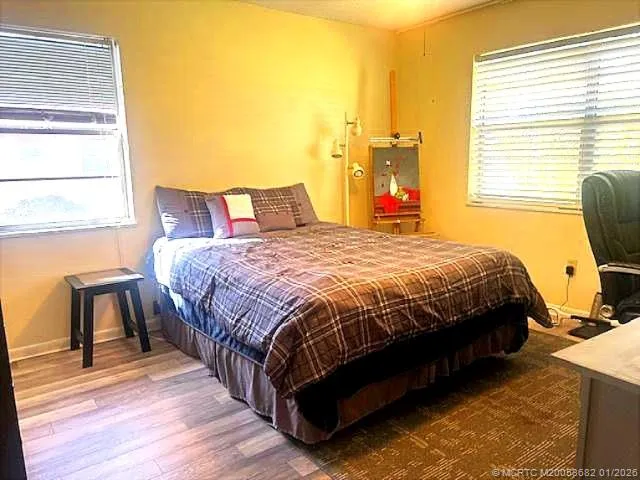 a bedroom with a bed a table and chair with the wooden floor