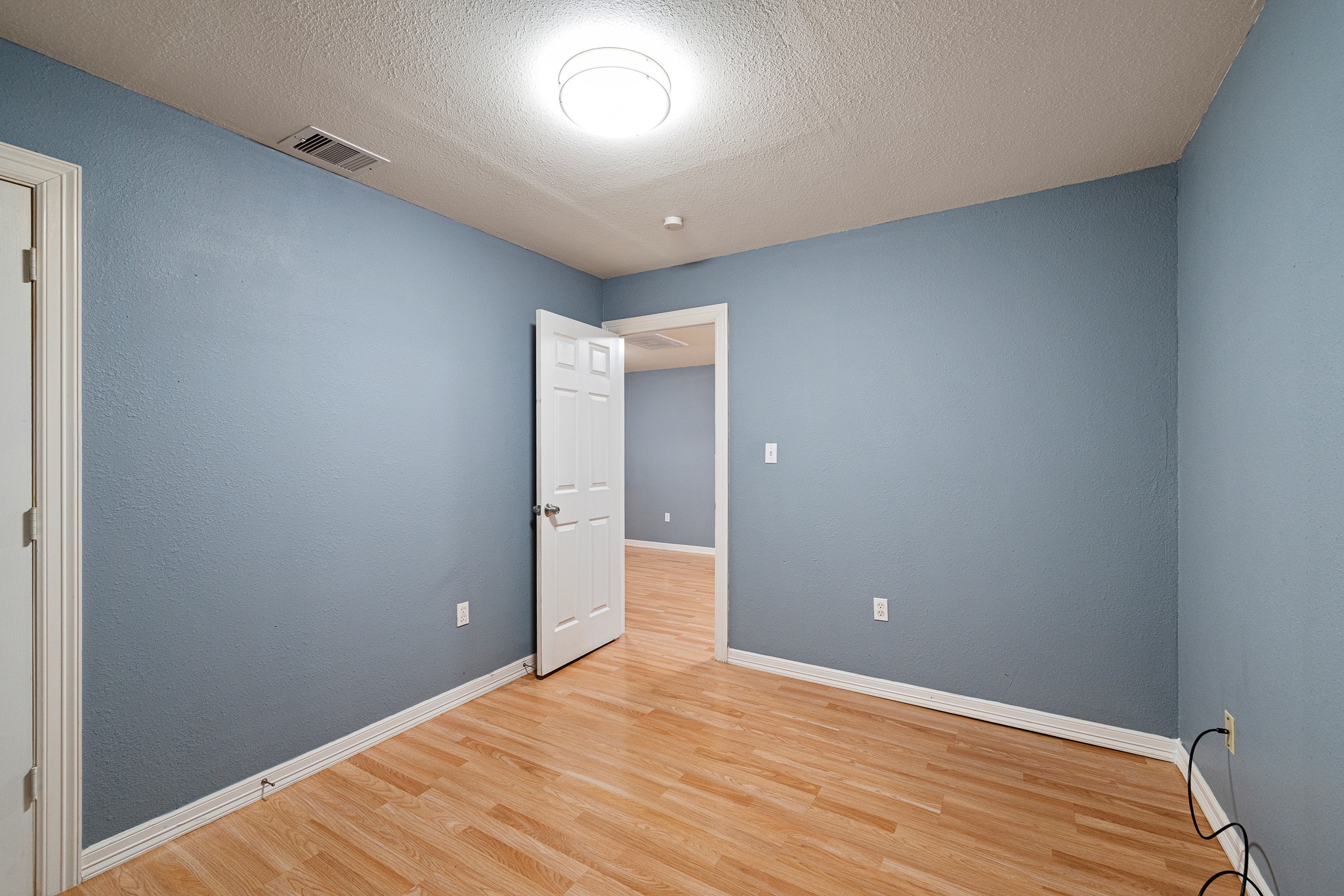 7815 Harding Street, Unit B Houston, TX 77012 - Photo 17 of 21 Experience tranquility in Bedroom 1, featuring soothing blue walls, warm flooring, and ample natural light for a perfect retreat.