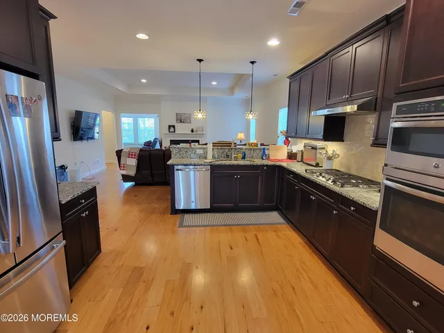 a large kitchen with wooden floors stainless steel appliances and a counter space