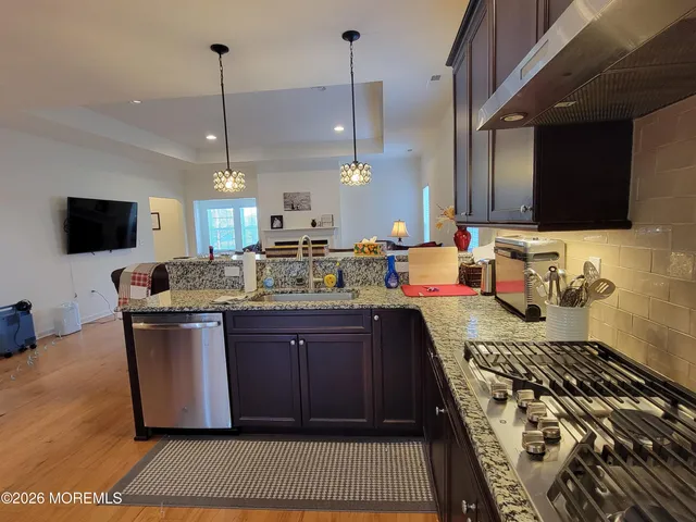 a kitchen with stainless steel appliances granite countertop a stove a sink and a wooden floors