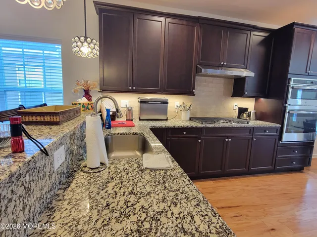 a kitchen with granite countertop a stove a oven a sink dishwasher and cabinets