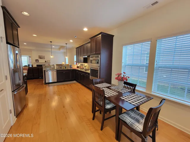 a living room with stainless steel appliances furniture a rug and a kitchen view