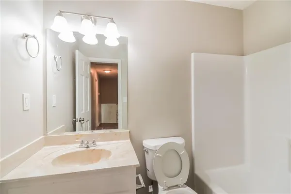 a bathroom with a granite countertop sink a toilet and mirror