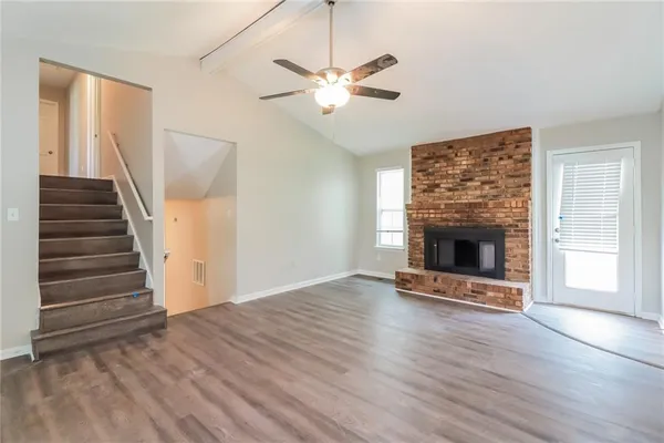 a view of an empty room with wooden floor fireplace and a window