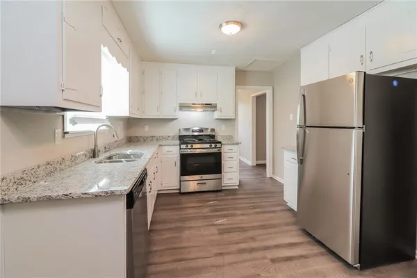 a kitchen with granite countertop a refrigerator stove top oven and sink