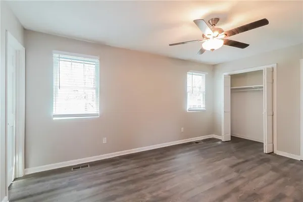 an empty room with wooden floor fan and windows
