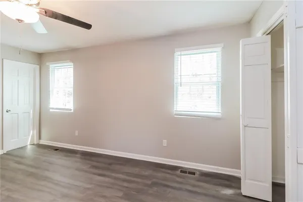 an empty room with wooden floor and windows