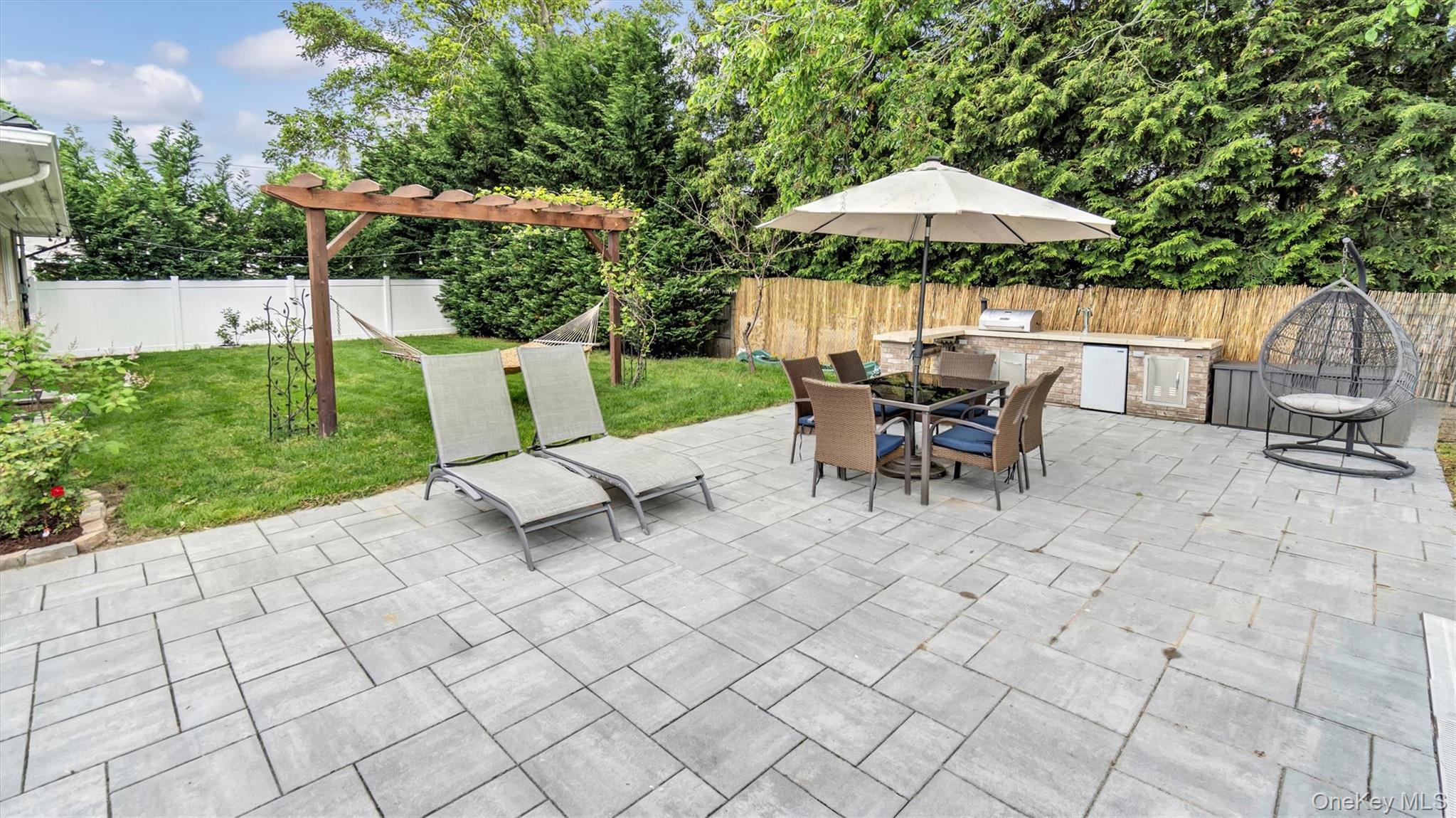 143 Hallock Street Riverhead, NY 11901 - Photo 4 of 39 a view of a patio with table and chairs under an umbrella with a barbeque grill and plants