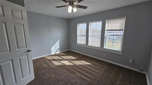 an empty room with a ceiling fan and entryway